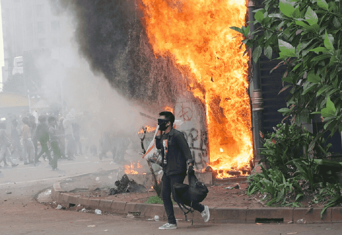 Protester in front of building on fire